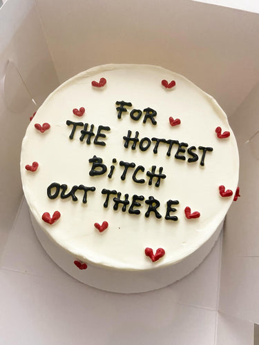 Бяла кръгла торта с надпис 'For THE HOTTEST BiTCH OUT THERE'