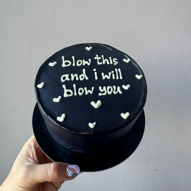Кръгла черна торта с бял надпис 'blow this and i will blow you'