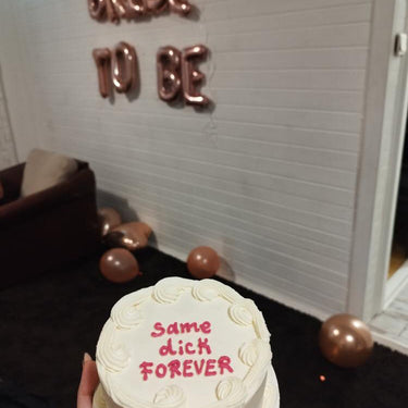 Кръгла бяла торта с кремав кант и надпис "same dick FOREVER".