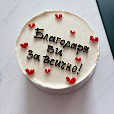 Бяла кръгла торта с надпис "Благодаря ви за всичко!" и декорация със сърца.