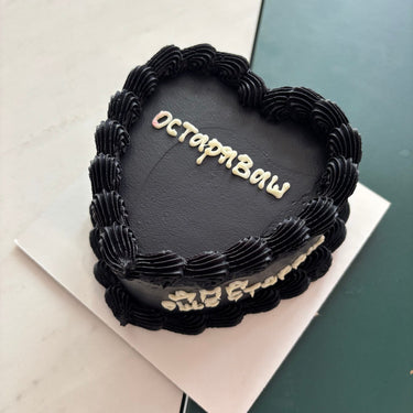 A black heart-shaped cake with a cream border and the side inscription GETTING OLD.