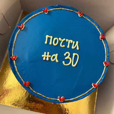 Кръгла синя торта с кремав кант и надпис 'почти на 30' отгоре.
