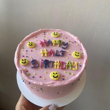 Кръгла розова торта с рисунка и надпис HAPPY HALF BIRTHDAY за полу-рожден ден на бебе.