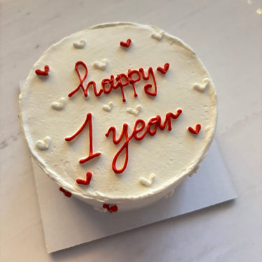 Кръгла бяла торта с надпис 'happy 1 year' за годишнина, без допълнителна украса