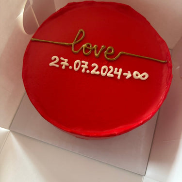 Round red cake with a decorative gold inscription