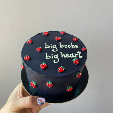 Кръгла морскосиня торта с надпис 'big boobs big heart', украсена с ягоди върху глазурата.
