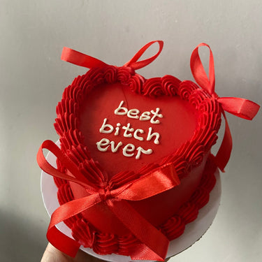 Червена торта сърце с панделки, кремав кант и надпис 'best bitch ever'