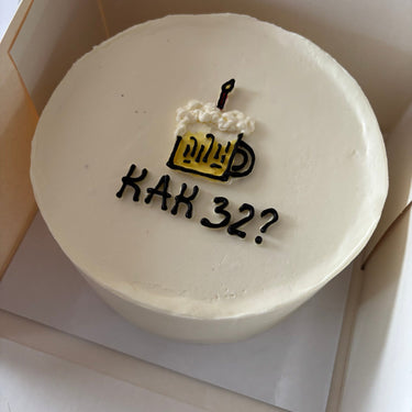 Кръгла бяла торта с рисунка и надпис 'КАК 32?' в тъмни букви