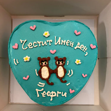 Торта сърце в ментов цвят с рисунка на видри и надпис 'Честит Имен ден, Георги'.