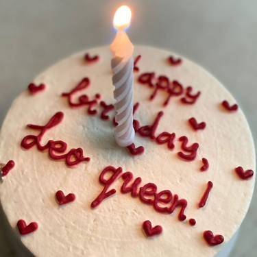 Кръгла кремава торта с надпис 'Happy Birthday, Leo queen!' на повърхността, без допълнителна украса.